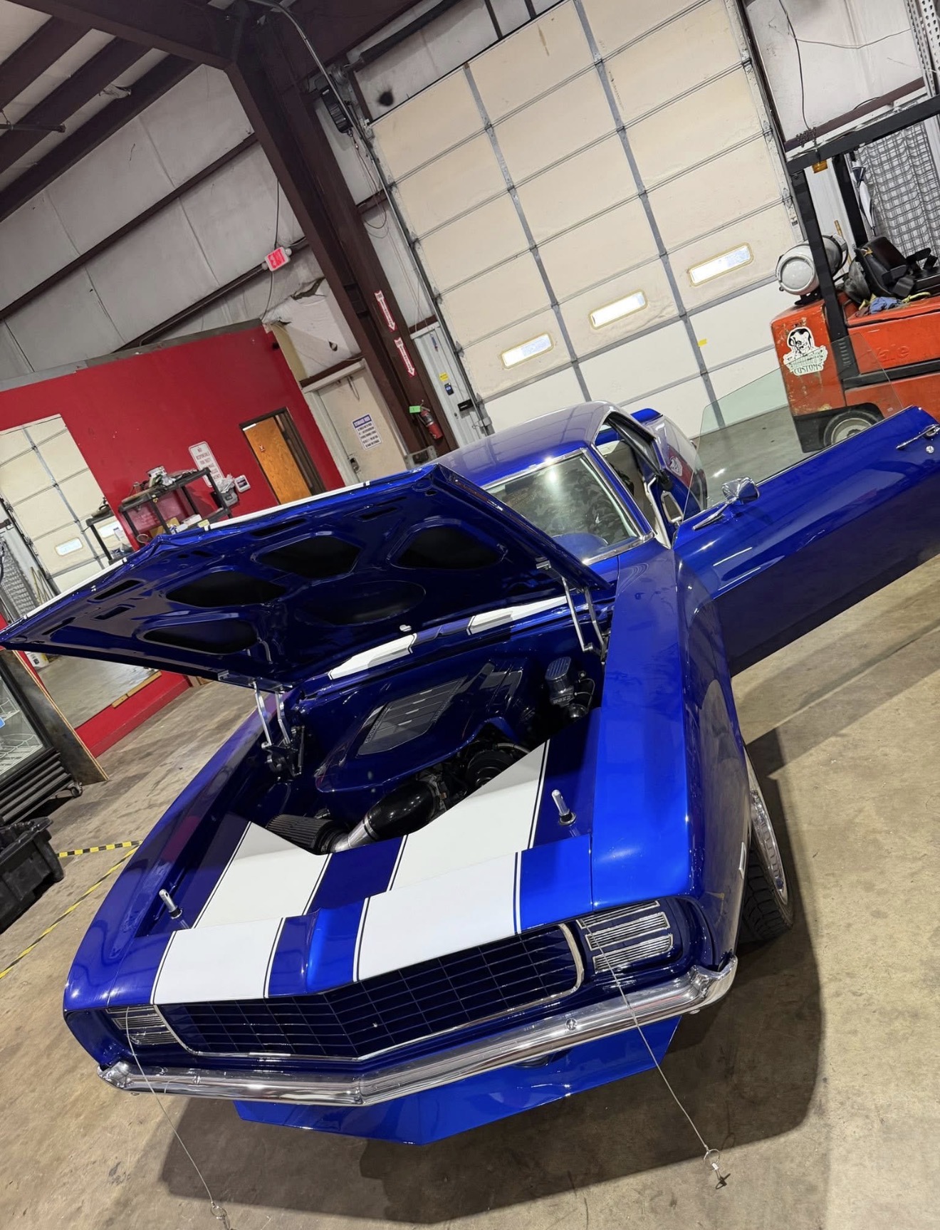 Candy blue 1969 Camaro pro-touring build with white stripes and open hood